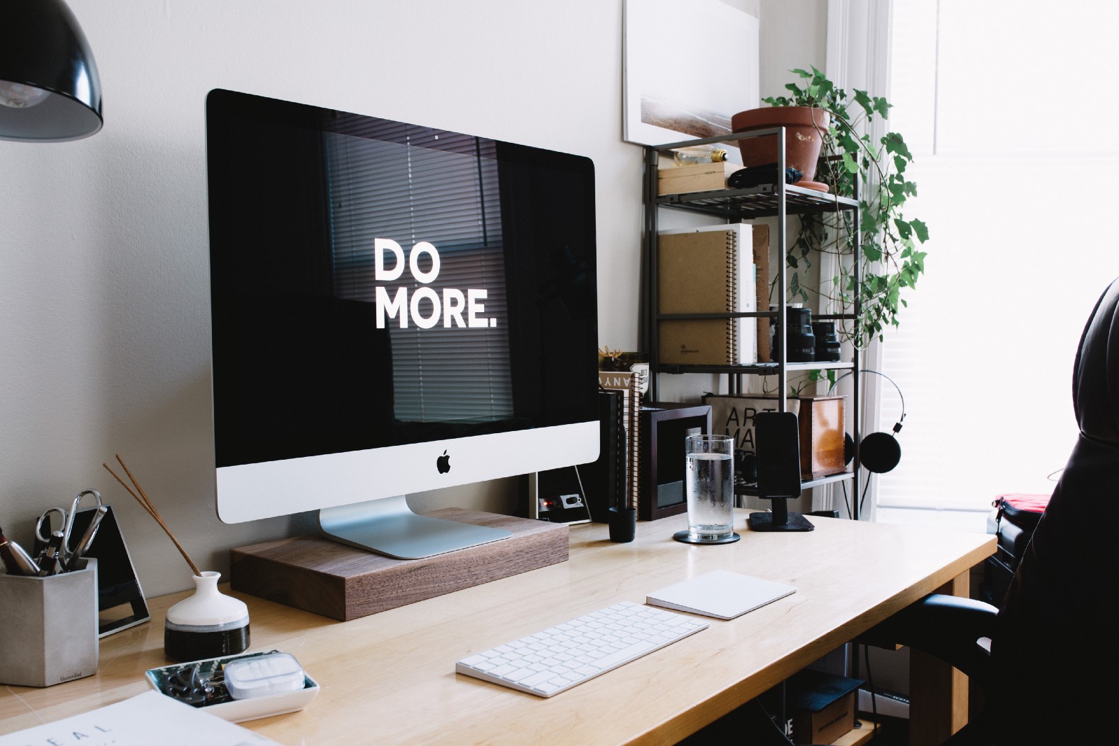 An iMac with “Do More” displayed on its screen on a wooden des